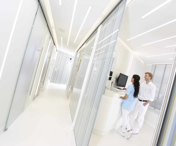Blick in ein Behandlungszimmer: Dr. Thomsen und eine Mitarbeiterin der Dental Protection Praxis stehen am Computer und diskutieren den Behandlungsplan.