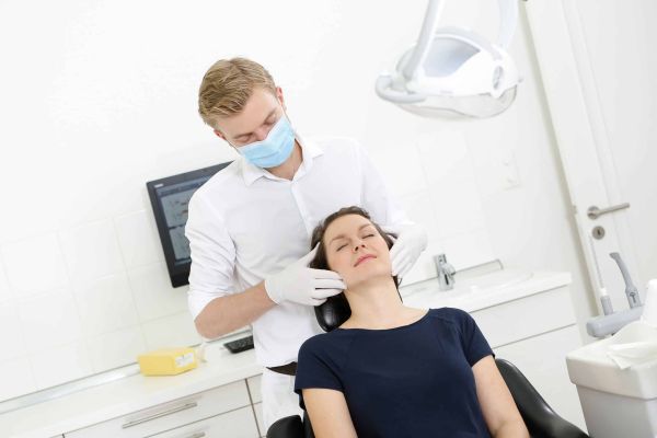 Dr. Thomsen führt eine CMD-Behandlung an einer Patientin durch.