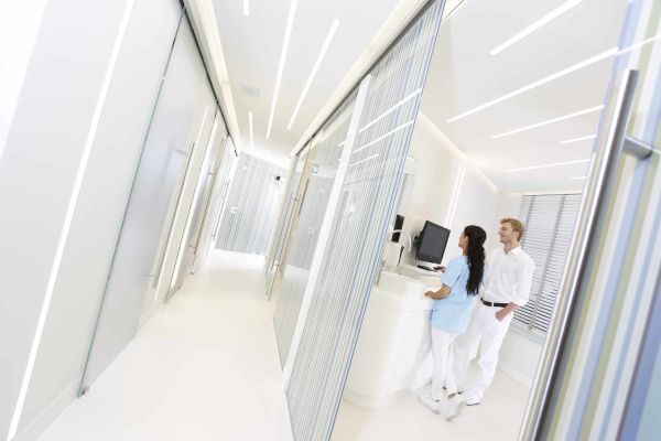 Blick in ein Behandlungszimmer: Dr. Thomsen und eine Mitarbeiterin der Dental Protection Praxis stehen am Computer und diskutieren den Behandlungsplan.