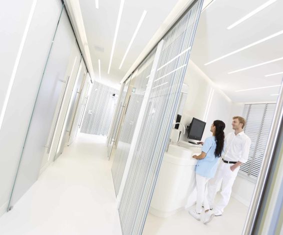 Blick in ein Behandlungszimmer: Dr. Thomsen und eine Mitarbeiterin der Dental Protection Praxis stehen am Computer und diskutieren den Behandlungsplan.