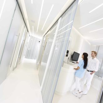 Blick in ein Behandlungszimmer: Dr. Thomsen und eine Mitarbeiterin der Dental Protection Praxis stehen am Computer und diskutieren den Behandlungsplan.