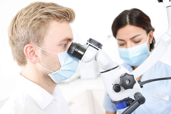 Dr. Thomsen arbeitet an einem Mikroskop während einer Behandlung in der Praxis Dental Protection in Hamburg-Eimsbüttel.