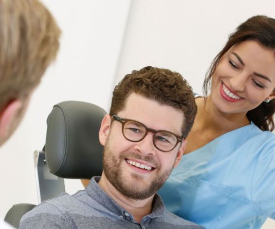 Behandlungsgespräch bei Dental Protection: Ein Patient im Gespräch mit einer Mitarbeiterin und Dr. Thomsen bei Dental Protection